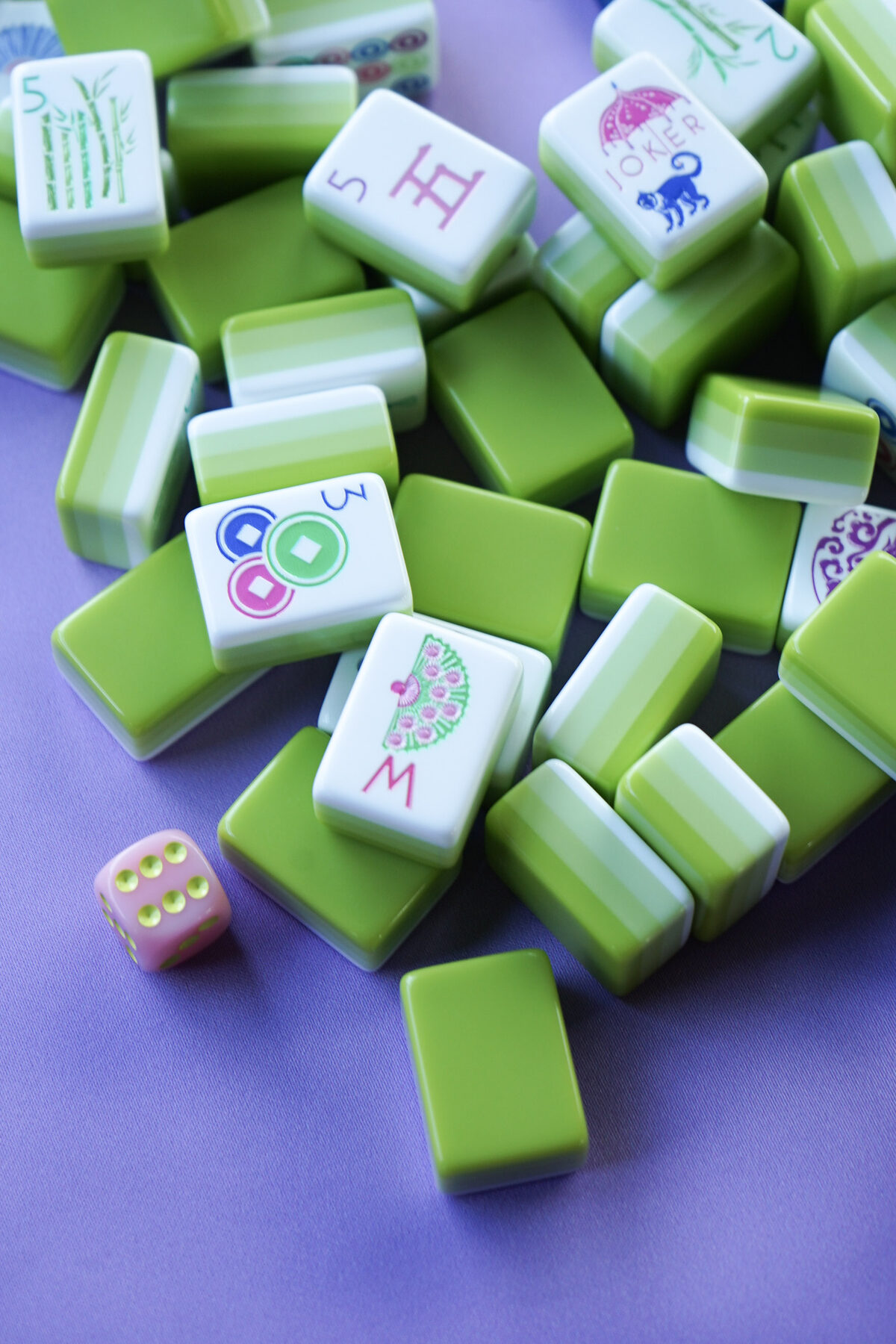A pile of bright green mahjong tiles on a lavender table