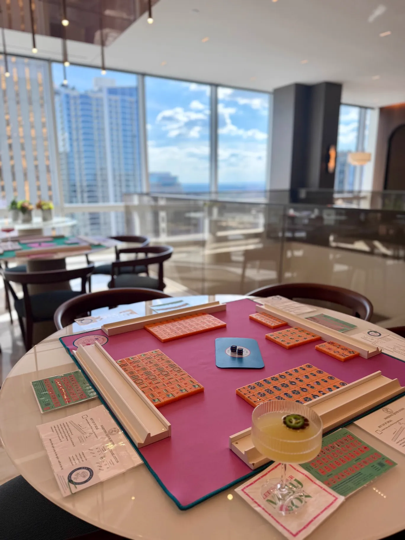 A glass of rosé in a Vaulted Oak Brewing glass next to mahjong tiles